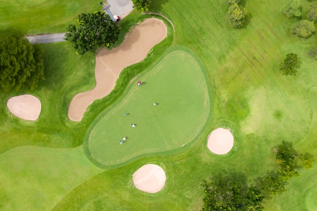 Vista aerea dei giocatori su un campo da golf verde. giocatore di golf che gioca sul mettere verde un giorno di estate. tempo di relax stile di vita di persone nel campo sportivo o attività di vacanza all'aperto.