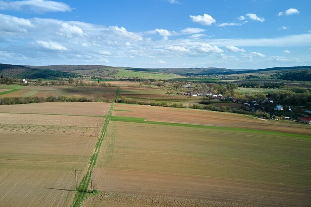 Aerial view of plowed agricultural fields with cultivated fertile soil prepared for planting crops between green woods in spring