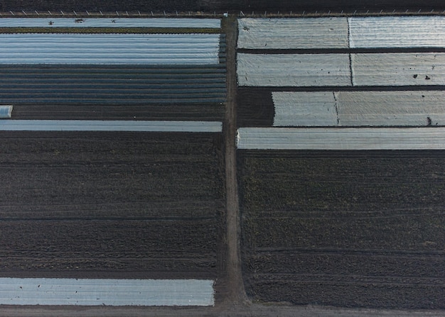 Aerial view of plowed spring field covered with polyethylene Agriculture and farming
