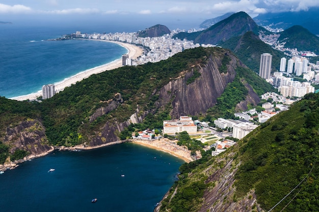 Aerial view of Praia Vermelha in the neighborhood of Urca in Rio de Janeiro Brazil The hills of Pao de Acucar and Urca Sunny day with some clouds at dawn Barra da Tijuca on the background