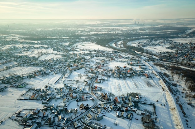 寒い冬の田舎の郊外の町の屋根が雪に覆われた民家の空撮