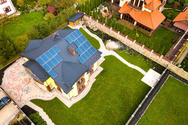 Вид с воздуха на частный дом с солнечными фотоэлектрическими панелями для производства чистой электроэнергии на крыше. Концепция автономного дома.