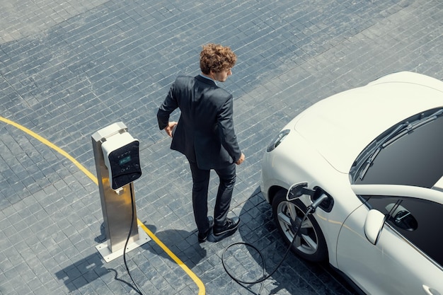 Aerial view of progressive businessman with EV car recharging battery