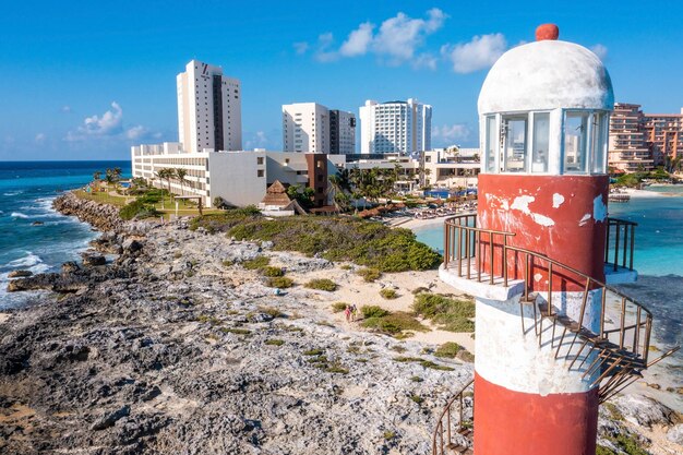 Aerial view of Punta Cancun Lighthouse. The Lighthouse adorned with white and red stripes and located in a rocky area.