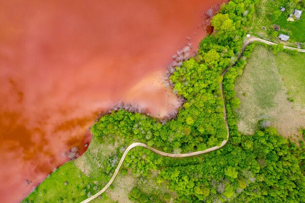 Вид с воздуха на красные сточные воды и зеленый лес