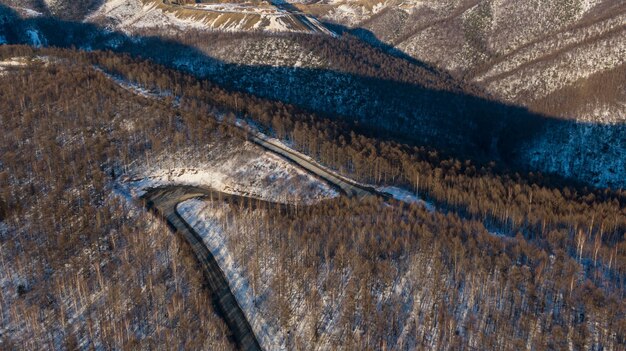 Vista aerea del fiume e foreste della taiga e strada nel paesaggio astratto primavera inverno della natura settentrionale con drone