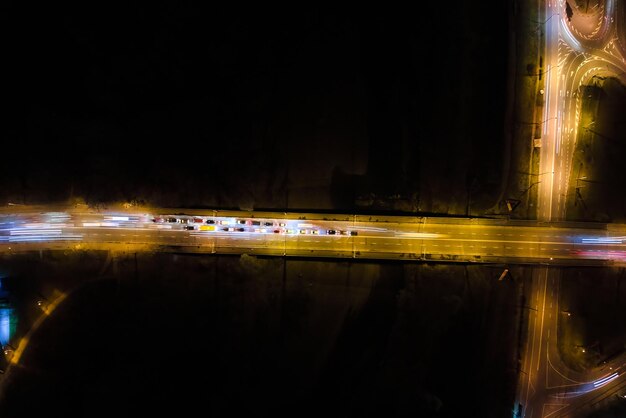 Aerial view of road intersection with fast moving heavy traffic at night Top view of urban transportation Rush hour with motion blurr car trail lights