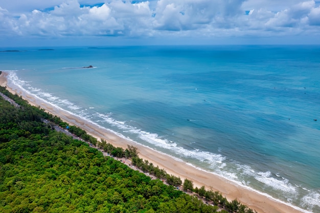 Aerial view of road between tree and great ocean with blue sky in Thailand