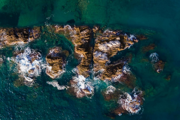 Aerial view of rocks under turquoise water