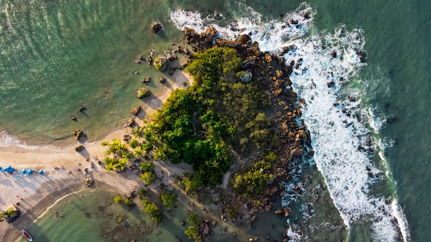 Aerial view of a rocky beach with a green island and the ocean in the background