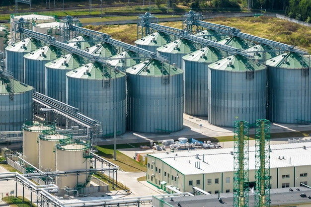 Aerial view on rows of agro silos granary elevator with seeds cleaning line on agroprocessing manufacturing plant for processing drying cleaning and storage of agricultural products