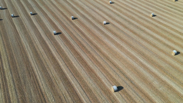 Aerial view over rural landscape hay bales in a farm field on a sunny day