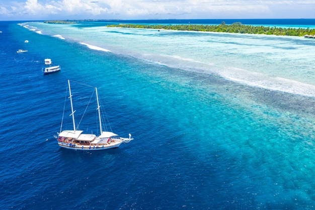 Aerial view of sailing boat anchoring on coral reef. Drone view, water sport theme. Exotic adventure