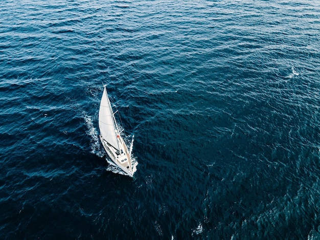 Aerial view of sailing ship yachts with white sails in windy condition in deep blue sea