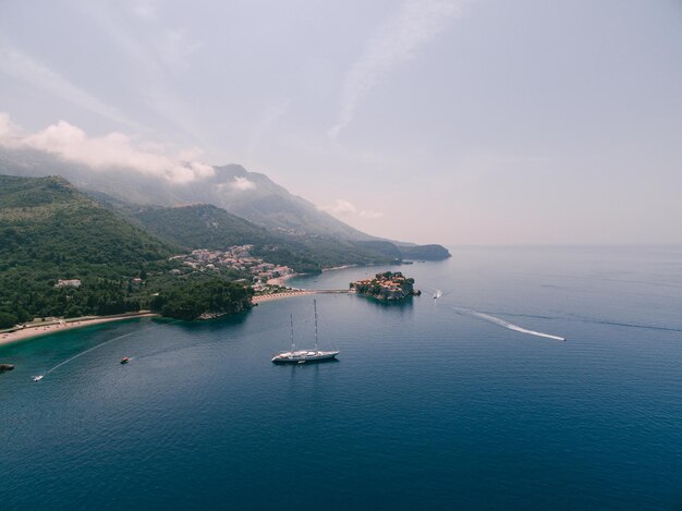 Aerial view of a sailing yacht against the backdrop of sveti stefan island