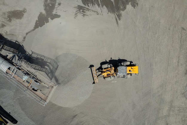 サンドローダーの空中写真は、ダンプトラックに岩をかき集めています