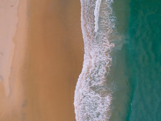 Aerial view sandy beach and waves beautiful tropical sea in the morning summer season image by aerial view drone shot high angle view top down sea waves