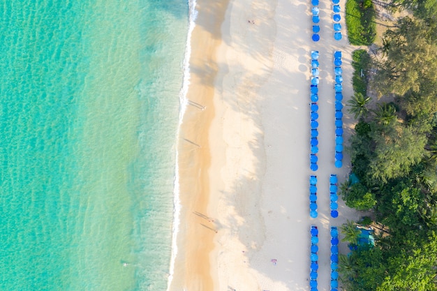 Aerial view of sandy beach with tourists swimming in beautiful clear sea water in Phuket, Thailand.