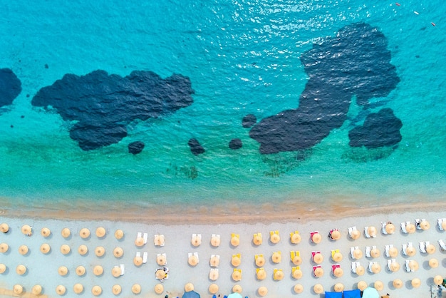 Aerial view of sandy coast mediterranean azure sea with beach umbrella