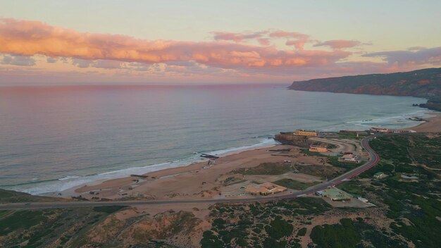 Foto vista aerea della costa panoramica mentre il tramonto proieta un caldo bagliore sulle scogliere e sulla spiaggia