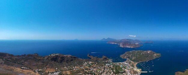 Aerial view of sea by city against blue sky