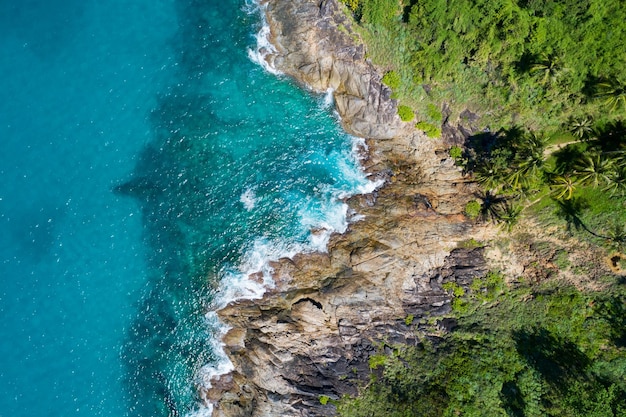 Aerial view of sea crashing waves white foaming waves on\
seashore rocks top view rocky coast mountain landscape view nature\
background