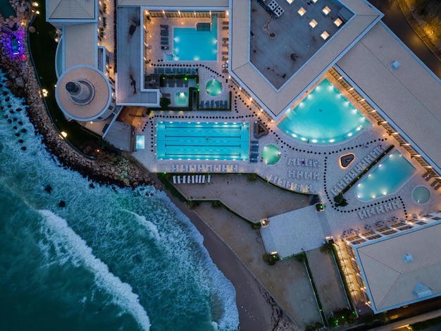 Aerial view of several pools in the spa center on a sea coast at night