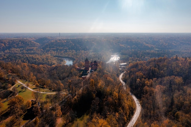 Aerial view of the Sigulda city in Latvia during golden autumn. Medieval castle in the middle of the forest.