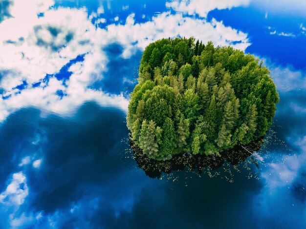 Aerial view over the small green forest island in blue lake in rural Finland