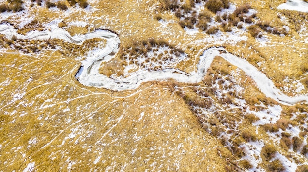Вид с воздуха на небольшой горный ручей зимой.