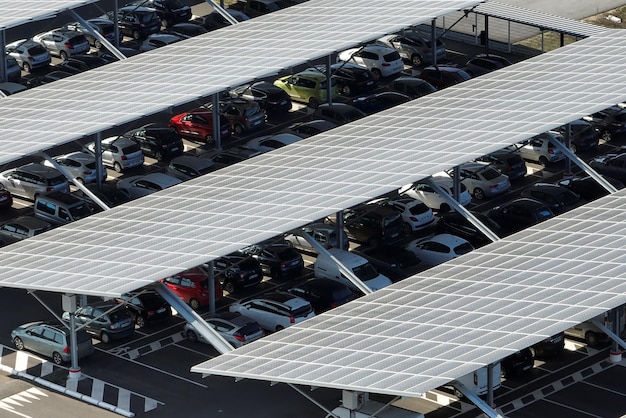 Воздушный вид солнечных панелей, установленных над парковкой с припаркованными автомобилями для эффективного производства чистой энергии
