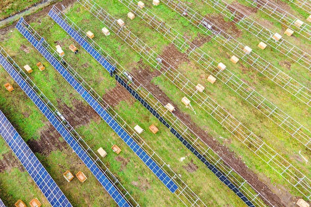 グリーンフィールドに建設中の太陽光発電所の航空写真。クリーンな生態学的エネルギー生産のための電気パネルの組み立て。