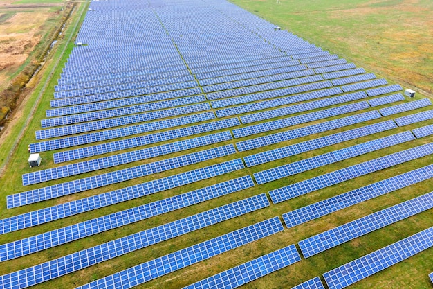 Aerial view of solar power plant on green field. Electric farm with panels for producing clean ecologic energy.