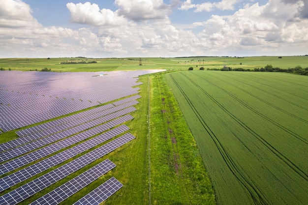 緑の野原にある太陽光発電所の航空写真。クリーンな生態学的エネルギーを生み出すための電気パネル。