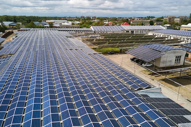 Aerial view of solar power plant with blue photovoltaic panels\
mounted on industrial building roof for producing green ecological\
electricity production of sustainable energy concept