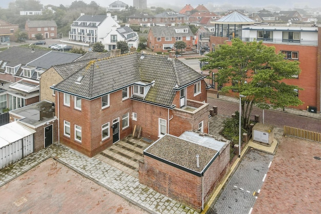 An aerial view of some houses in the city with rain falling down on the roof and trees to the right