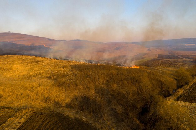 봄에 건조한 풀이 불타는  ⁇ 의 공중 사진 초원에서 불과 연기가 자연 오염과 위험 관목과 일반 폐기물이 루마니아에서 불타고 있습니다.