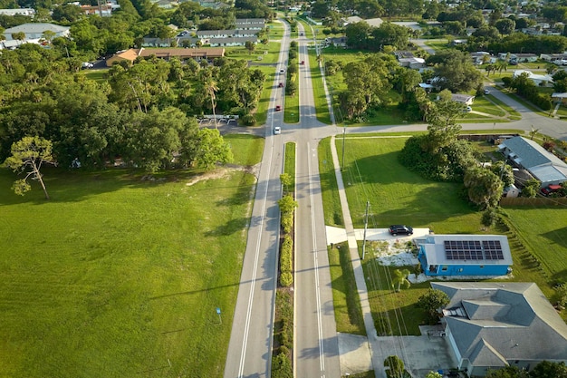 Aerial view of street traffic with driving cars in small town America suburban landscape with private homes between green palm trees in Florida quiet residential area