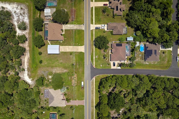 Aerial view of street traffic with driving cars in small town American suburban landscape with private homes between green palm trees in Florida quiet residential area