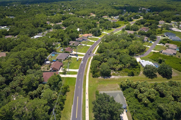 Aerial view of street traffic with driving cars in small town American suburban landscape with private homes between green palm trees in Florida quiet residential area