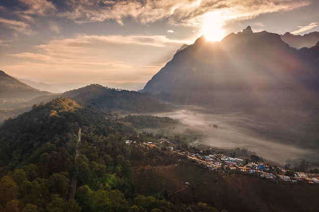Ban Na Lao Mai Chiang Dao Chiang Mai Thailand의 열대 우림 언덕에 있는 안개와 지역 마을이 있는 Doi Luang Chiang Dao 산맥 위로 일출의 공중 전망