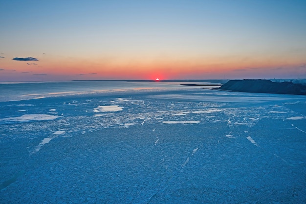 Foto vista aerea del tramonto sul paesaggio invernale del mare ghiacciato in riva al mare durante il tramonto vista dall'alto