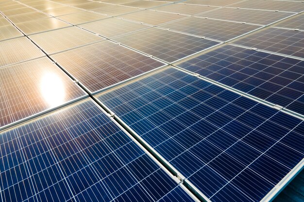 Aerial view of surface of blue photovoltaic solar panels mounted on building roof for producing clean ecological electricity. Production of renewable energy concept.