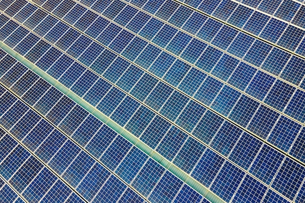 Aerial view of surface of blue photovoltaic solar panels mounted on building roof for producing clean ecological electricity. Production of renewable energy concept.