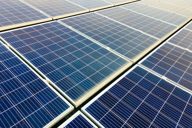 Aerial view of surface of blue photovoltaic solar panels mounted on building roof for producing clean ecological electricity. Production of renewable energy concept.