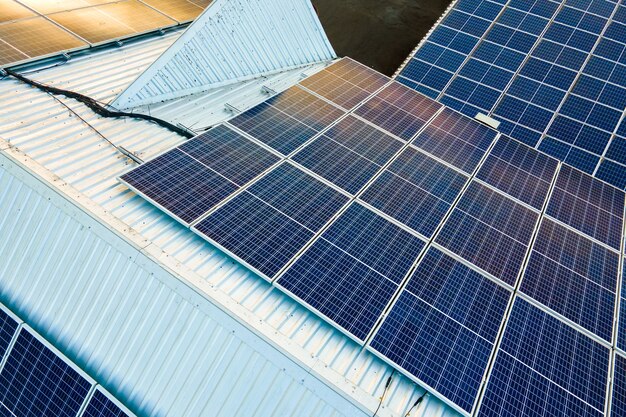 Aerial view of surface of blue photovoltaic solar panels mounted on building roof for producing clean ecological electricity. Production of renewable energy concept.