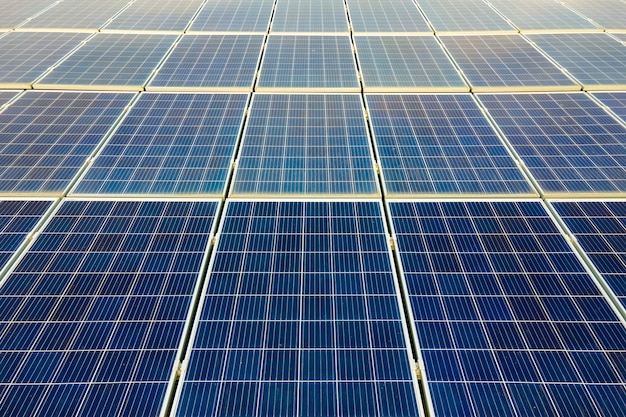 Aerial view of surface of blue photovoltaic solar panels mounted on building roof for producing clean ecological electricity. Production of renewable energy concept.