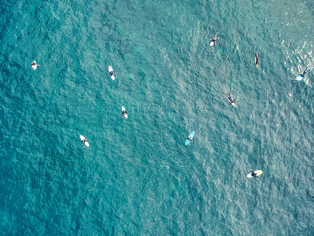 Aerial view of surfers in the azure waters of the Atlantic ocean background