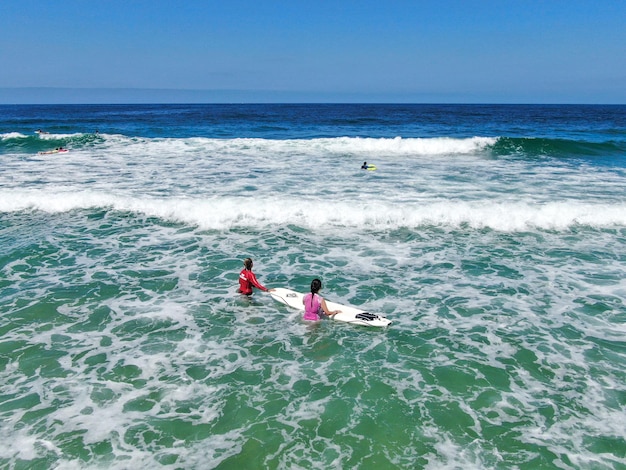 Aerial view of surfers waiting and paddling to the waves in blue water La Jolla California USA