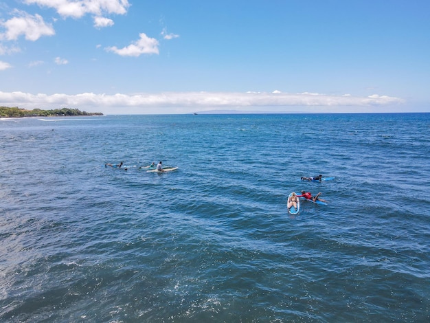 Вид с воздуха на серферов и волны в кристально-голубом океане на Мауи, Гавайи, США